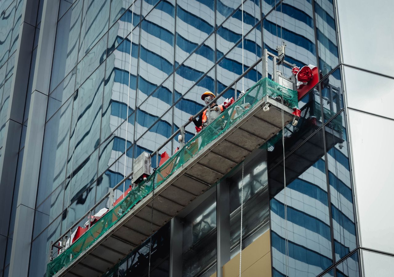 Urban worker cleaning windows on a high-rise in Ho Chi Minh City, Vietnam.